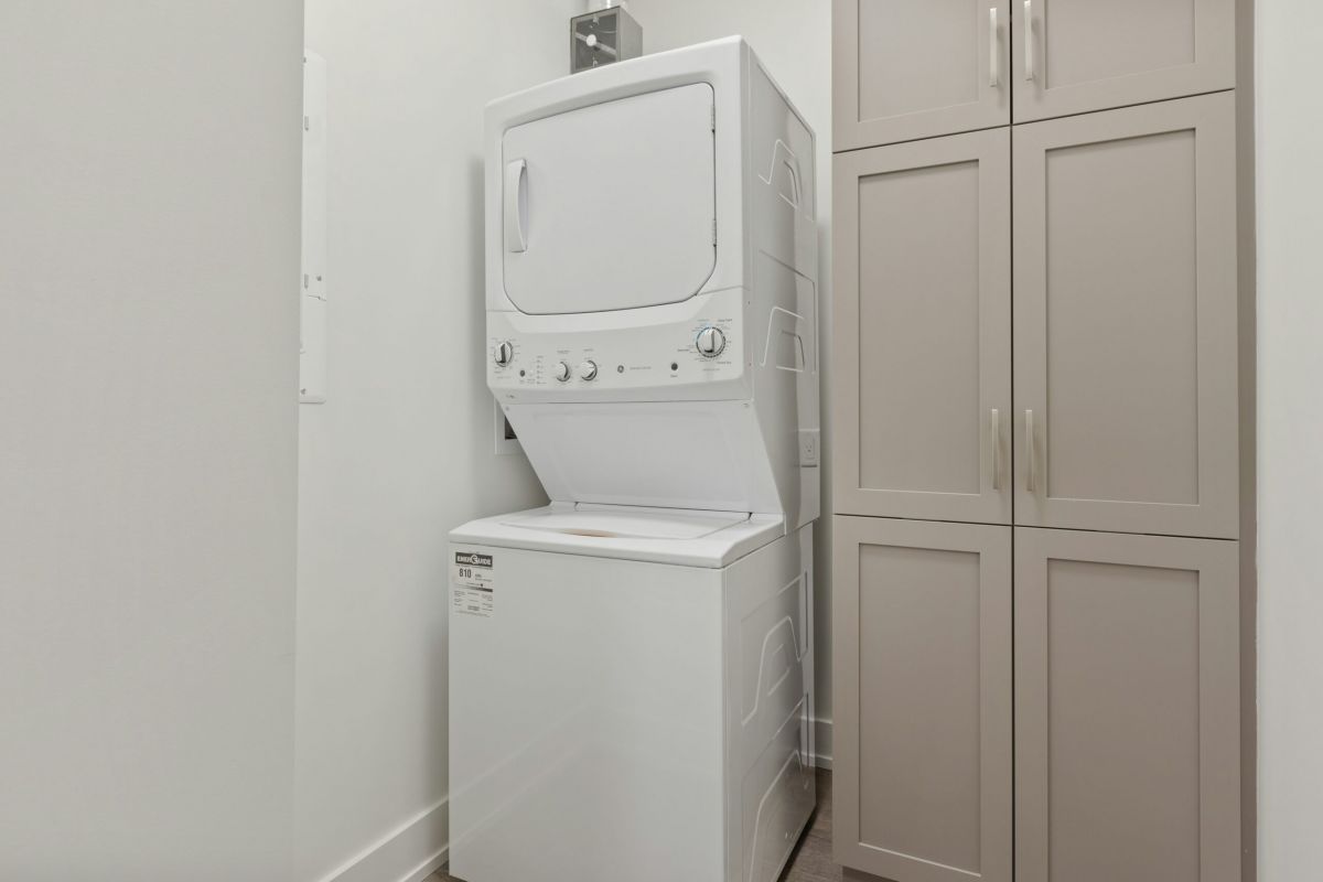 Laundry room with a washer, dryer, water heater, and bright white walls on a wood floor.