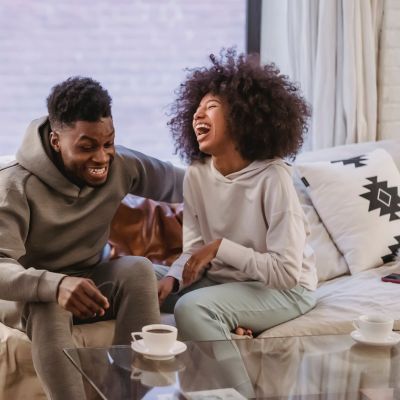 Laughing couple in loungewear on a couch