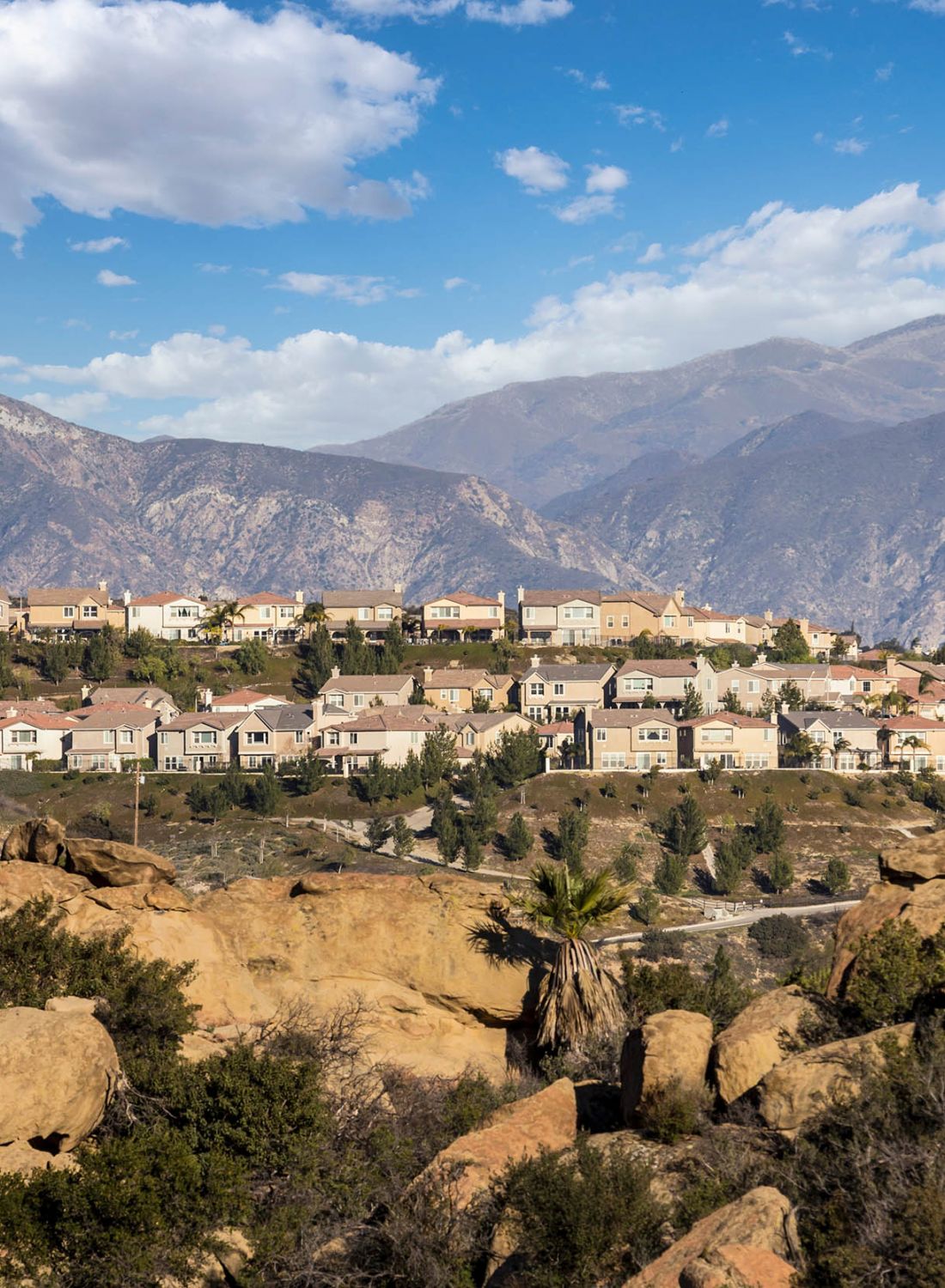 Housing community landscape, positioned amongst rocky open space and mountains on sunny day