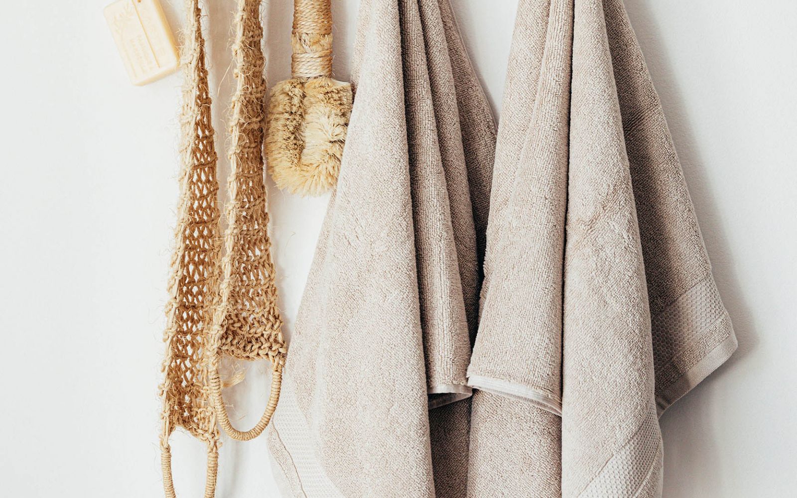 Natural loofa and soap and towels hanging from wooden peg board