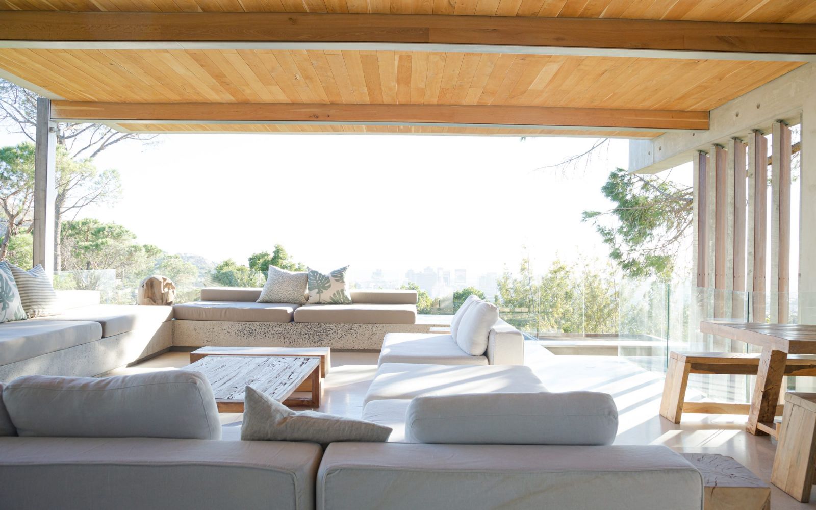 Modern indoor-outdoor patio with wood overhang, looking out a sunny view