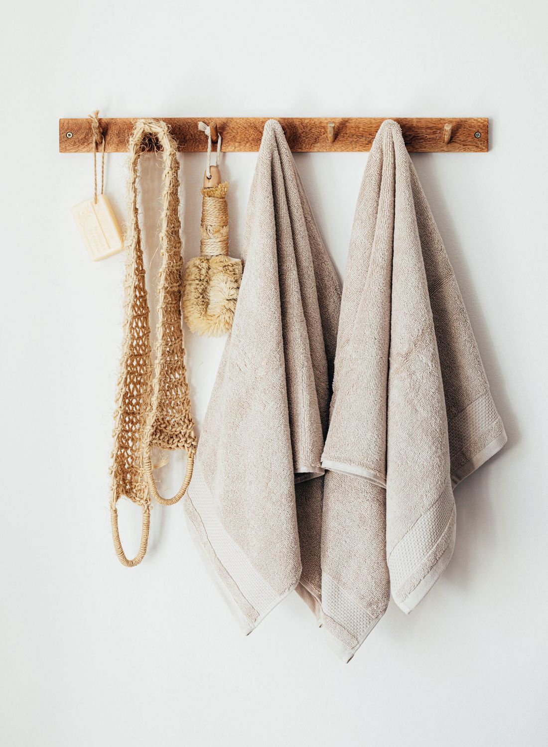 Natural loofa and soap and towels hanging from wooden peg board