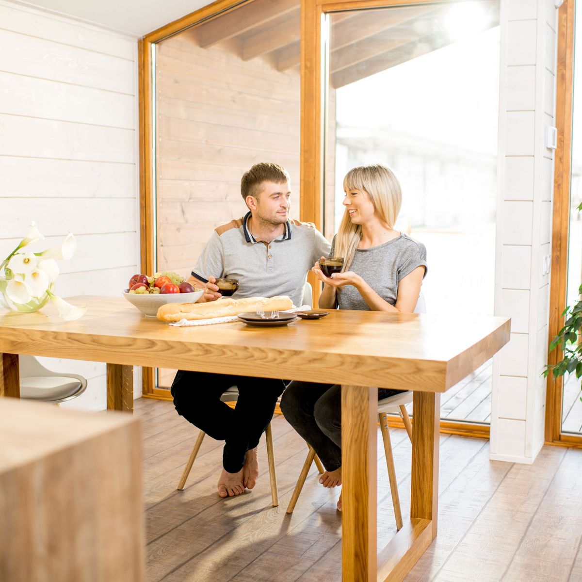 Couple sitting at a wooden table in light-filled kitchen area