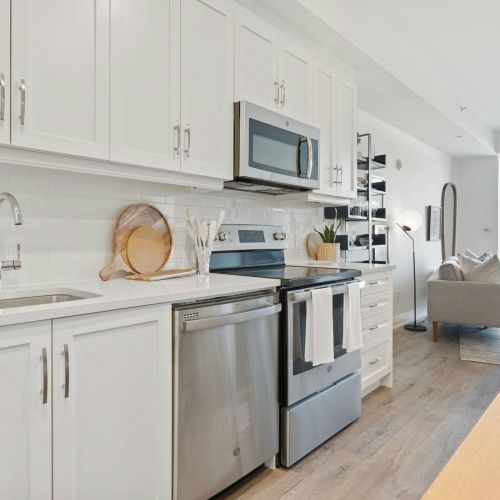 Xcelsior apartment theme modern kitchen with white backsplash and stainless steel appliances.